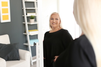 Photo of Mature woman looking in mirror at home