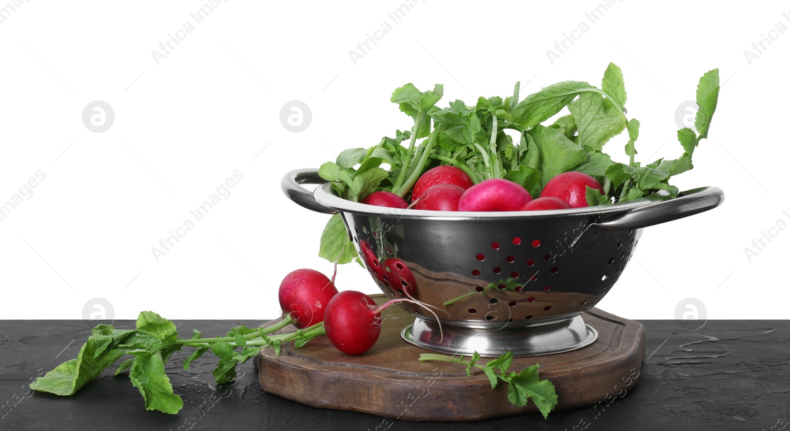 Photo of Metal colander with fresh radishes on black textured table against white background