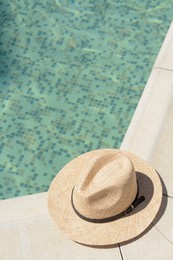 Photo of Stylish hat near outdoor swimming pool on sunny day, space for text. Beach accessory