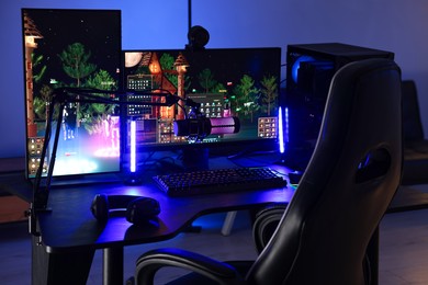 Photo of Playing video games. Stylish room interior with modern computer and gaming chair in neon lights