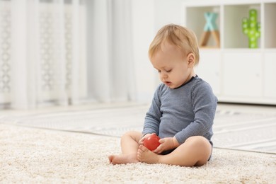 Photo of Children toys. Cute little boy playing with red ball on rug at home, space for text
