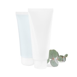 Tubes of hand cream and eucalyptus on white background