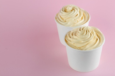 Photo of Cups with tasty frozen yogurt on pink background. Space for text