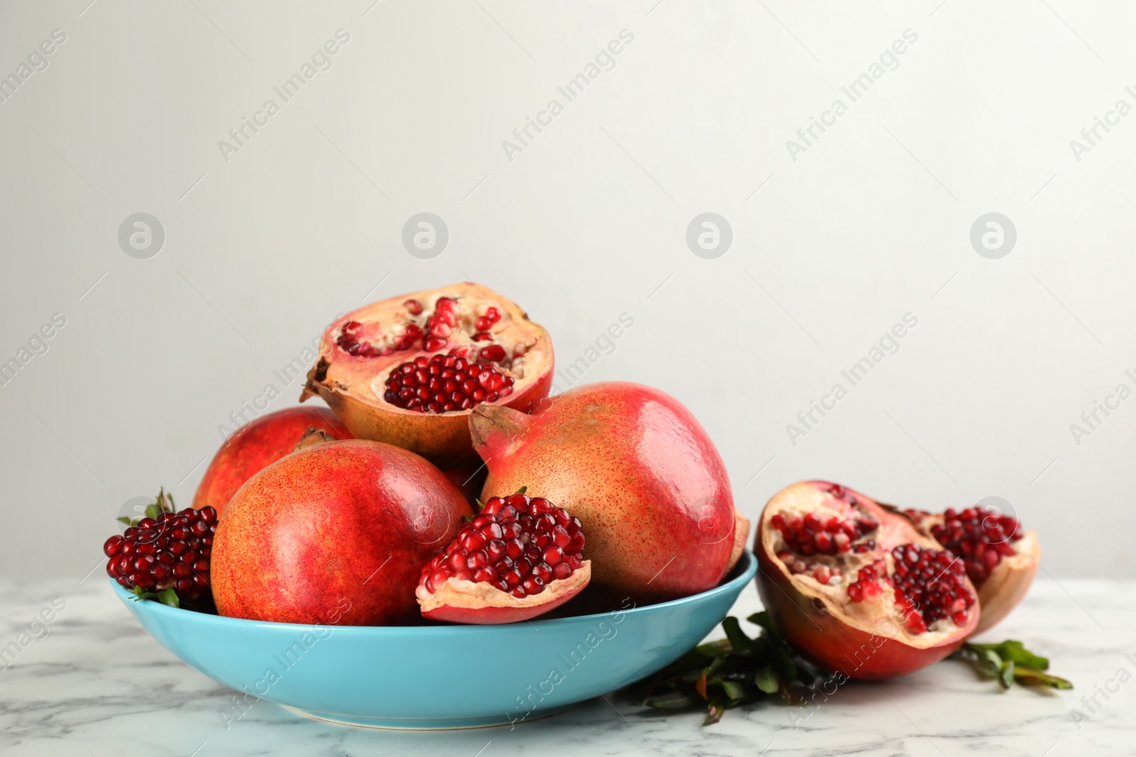 Photo of Delicious ripe pomegranates on white marble table