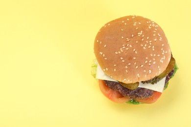Photo of Burger with delicious patty on yellow background, above view. Space for text