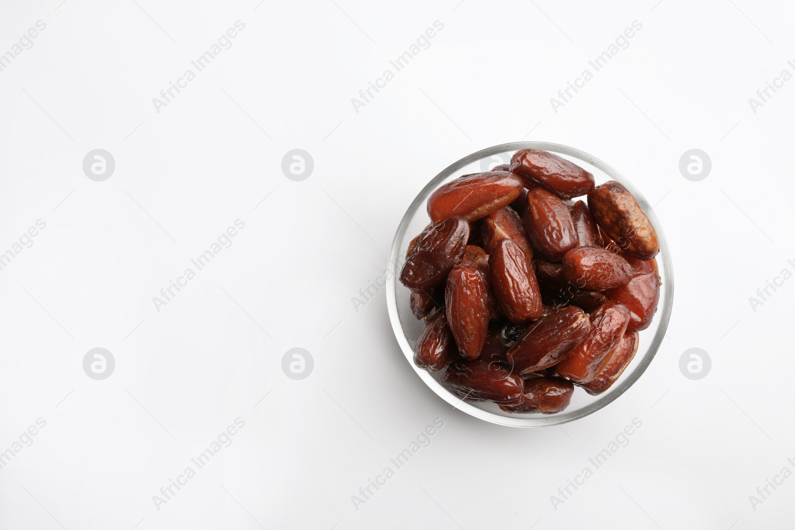 Photo of Bowl with sweet dried date fruits on white background, top view. Space for text