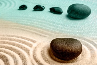 Image of Black stones on sand with pattern. Zen, meditation, harmony