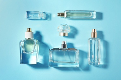 Bottles of perfume on color background, top view