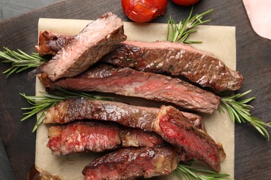 Photo of Delicious grilled beef with tomatoes and rosemary on table, top view