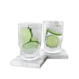 Photo of Glasses of lemonade and stylish stone cup coasters on white background