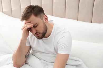 Photo of Young man suffering from migraine in bed