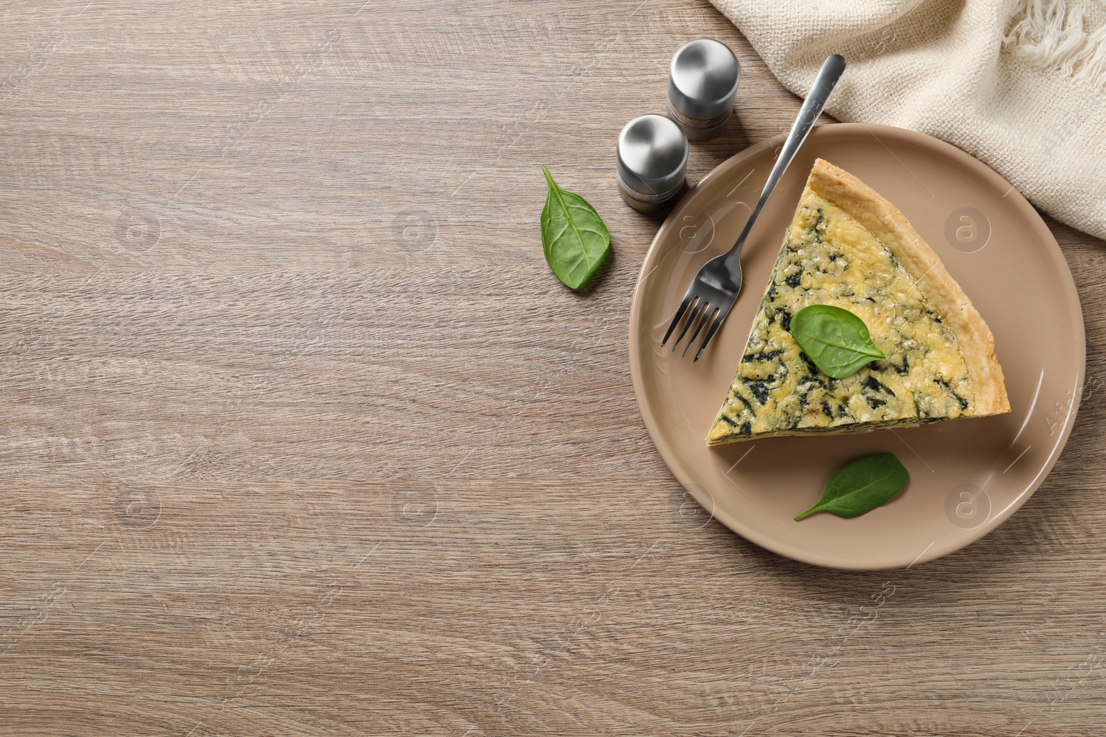 Photo of Piece of delicious homemade spinach pie and spices on wooden table, flat lay. Space for text