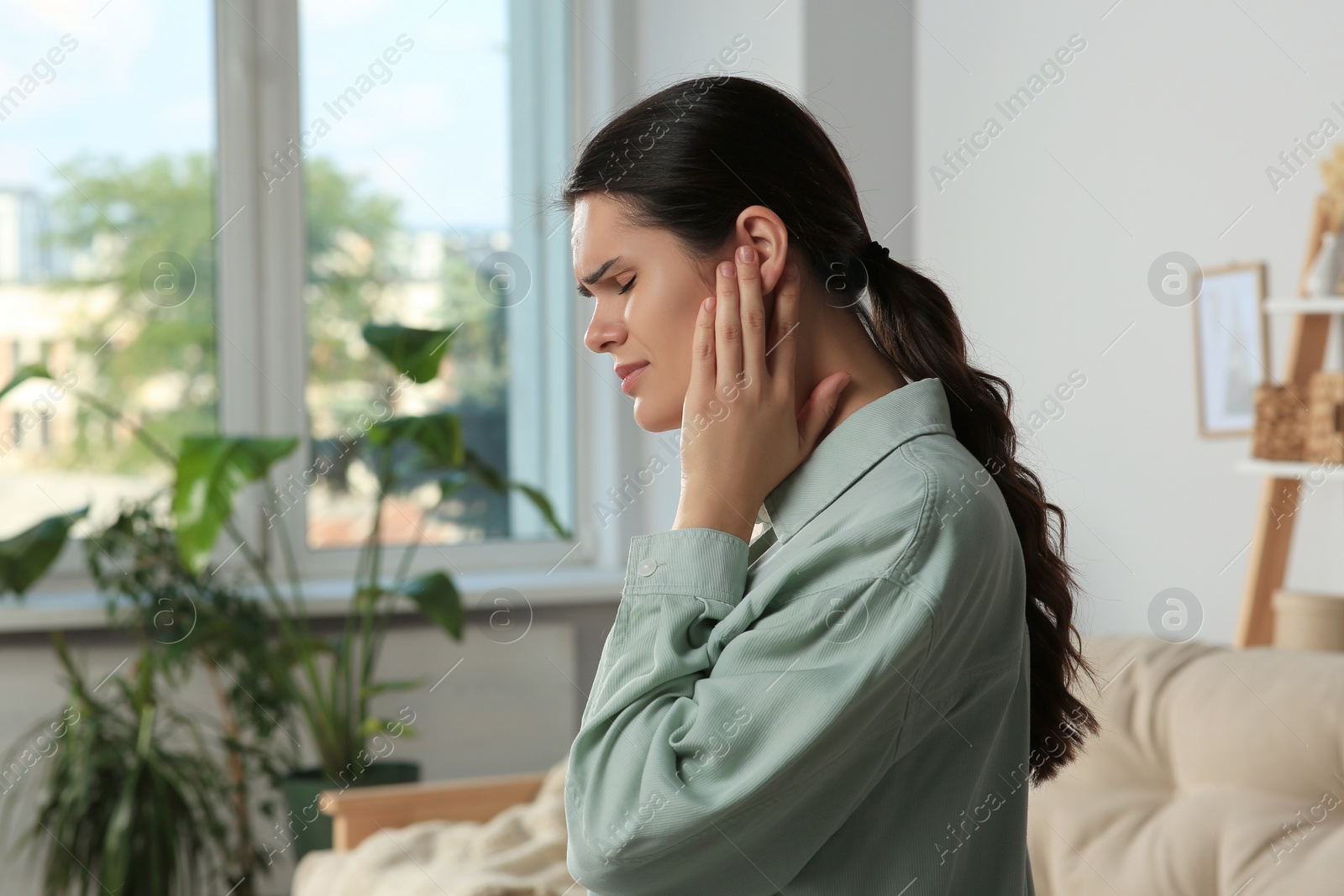 Photo of Young woman suffering from ear pain at home