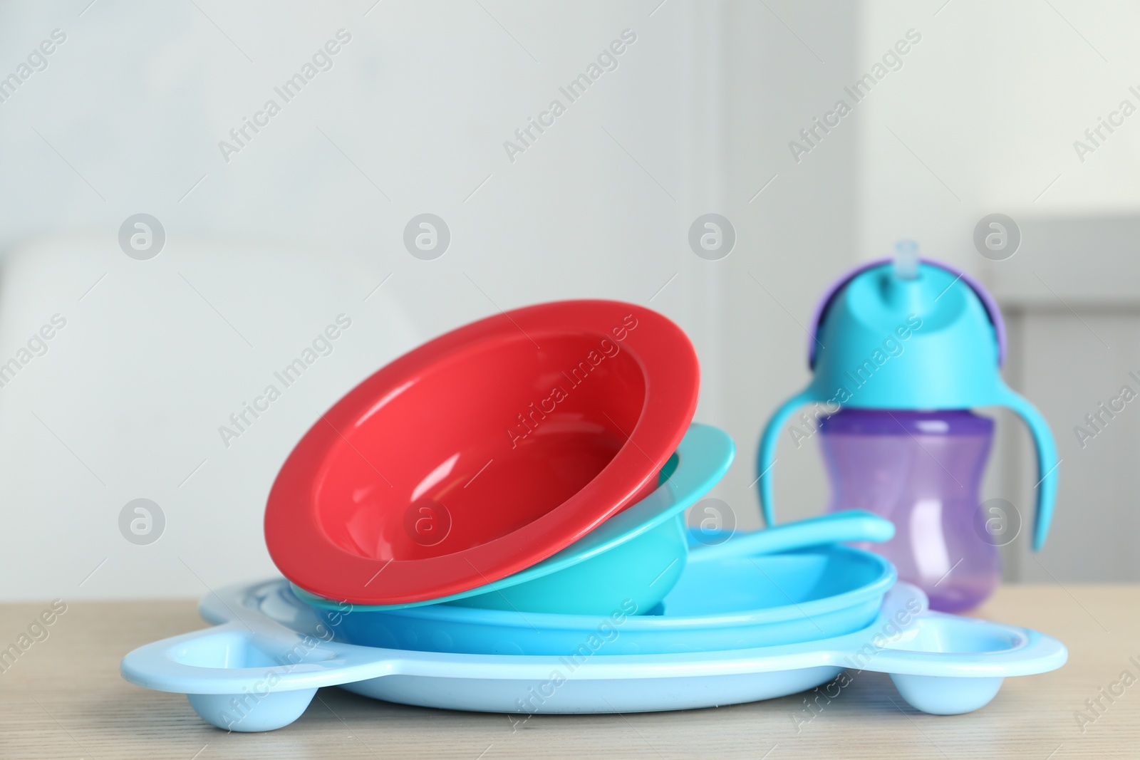 Photo of Set of plastic dishware on wooden table indoors. Serving baby food