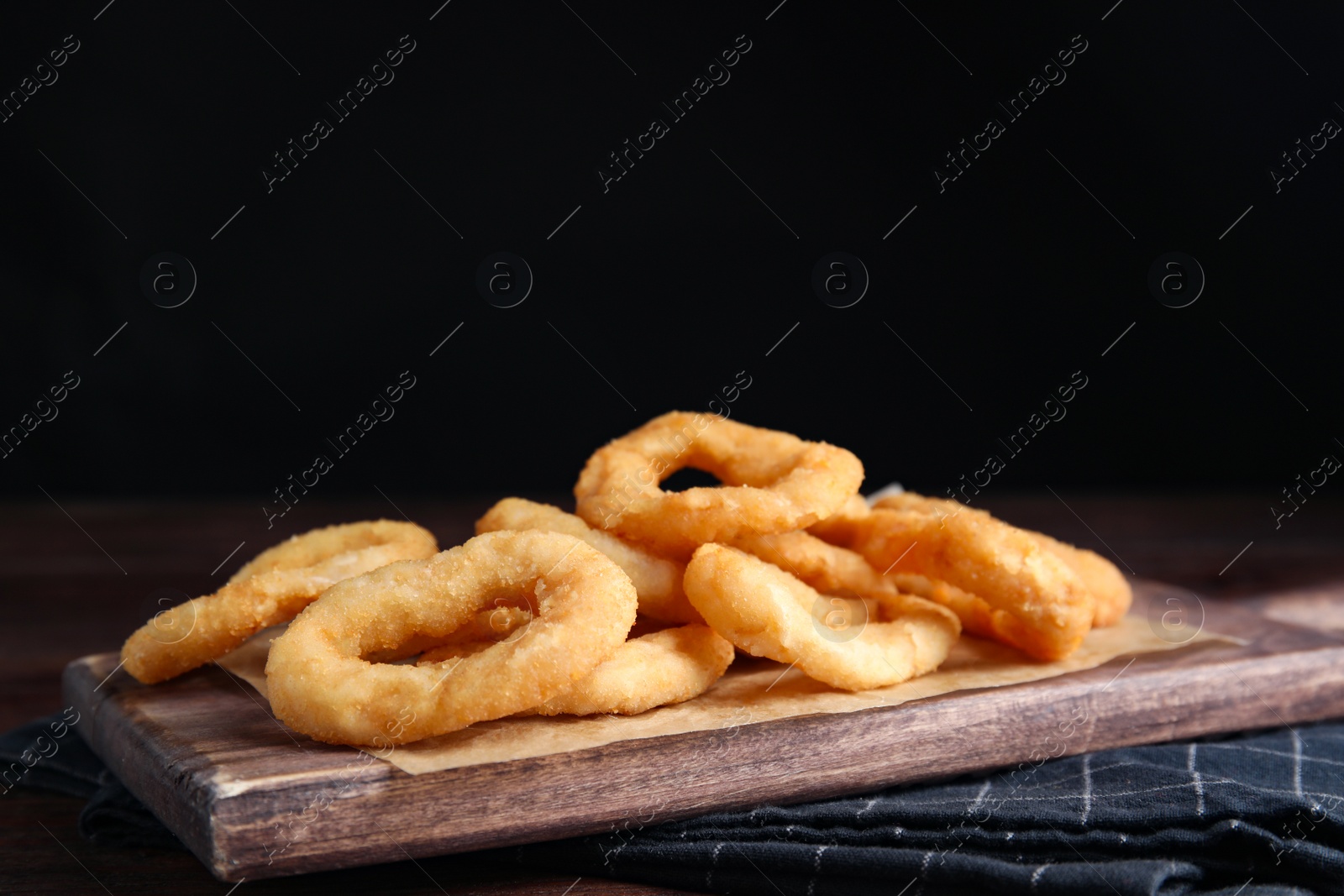 Photo of Fried onion rings served on wooden table