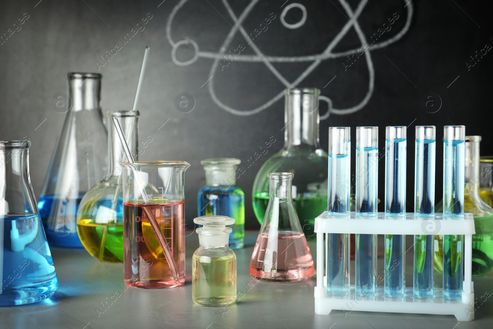 Photo of Laboratory glassware on table near chalkboard. Chemistry concept