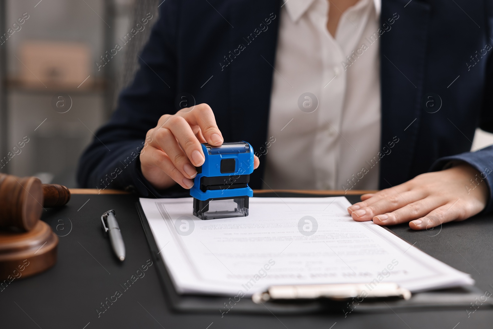 Photo of Notary stamping document at table in office, closeup