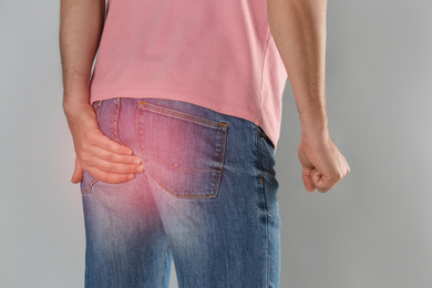 Image of Man suffering from hemorrhoid on light grey background, closeup
