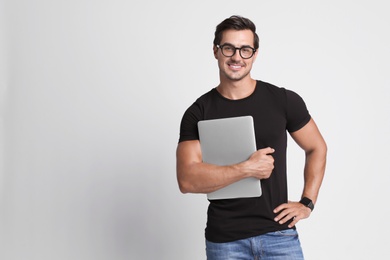 Photo of Handsome young man with laptop on grey background. Space for text