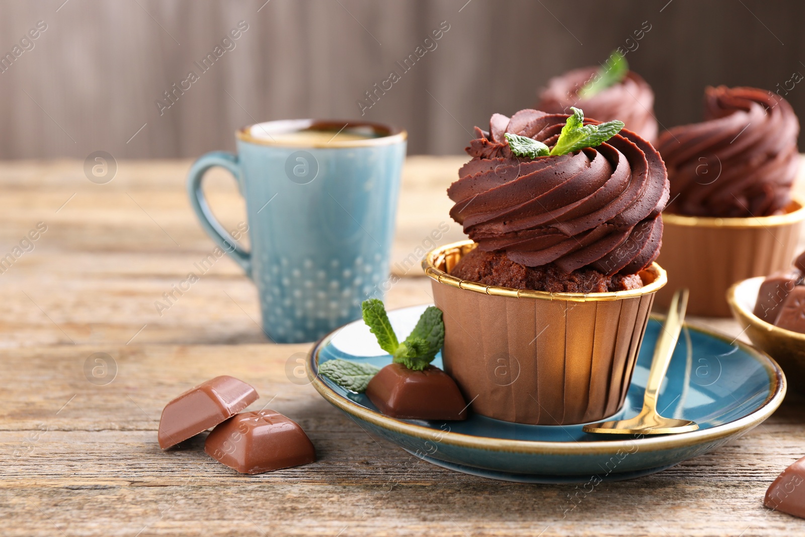 Photo of Delicious cupcake with mint and chocolate pieces on wooden table