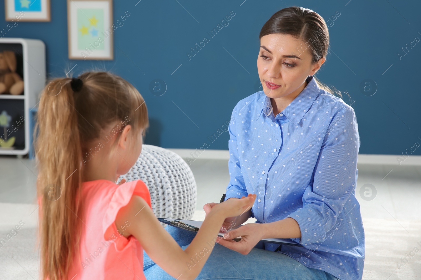 Photo of Female psychologist working with cute little girl in office