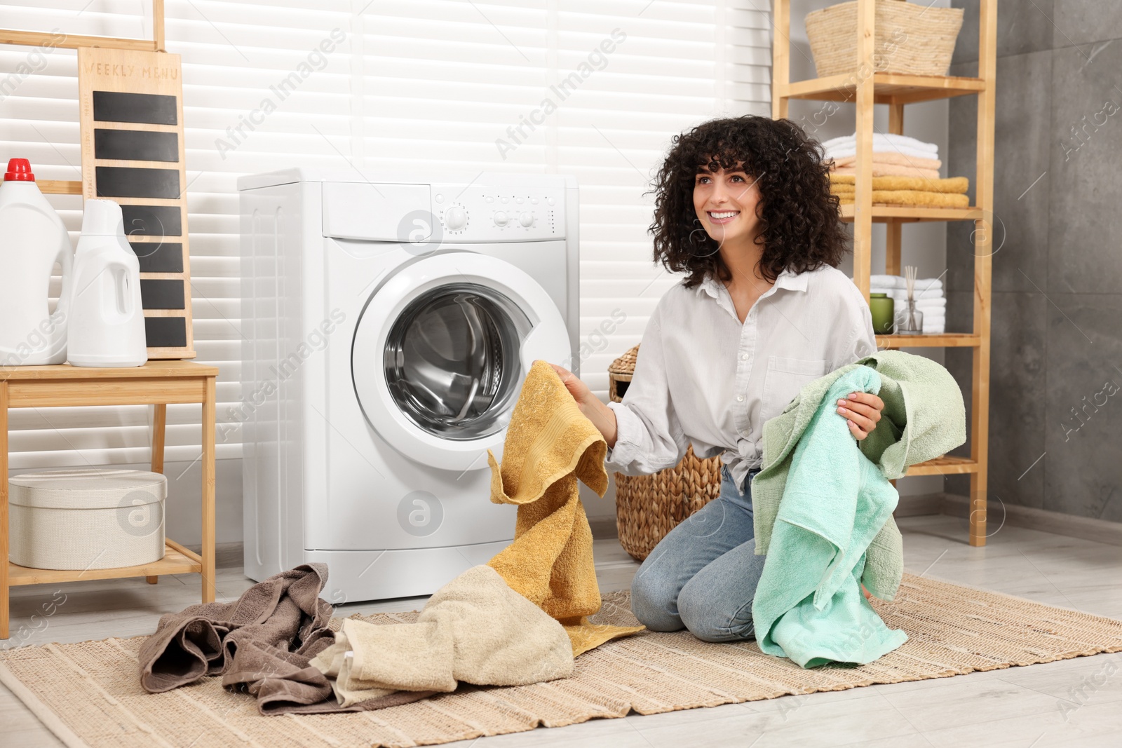 Photo of Woman with laundry near washing machine indoors