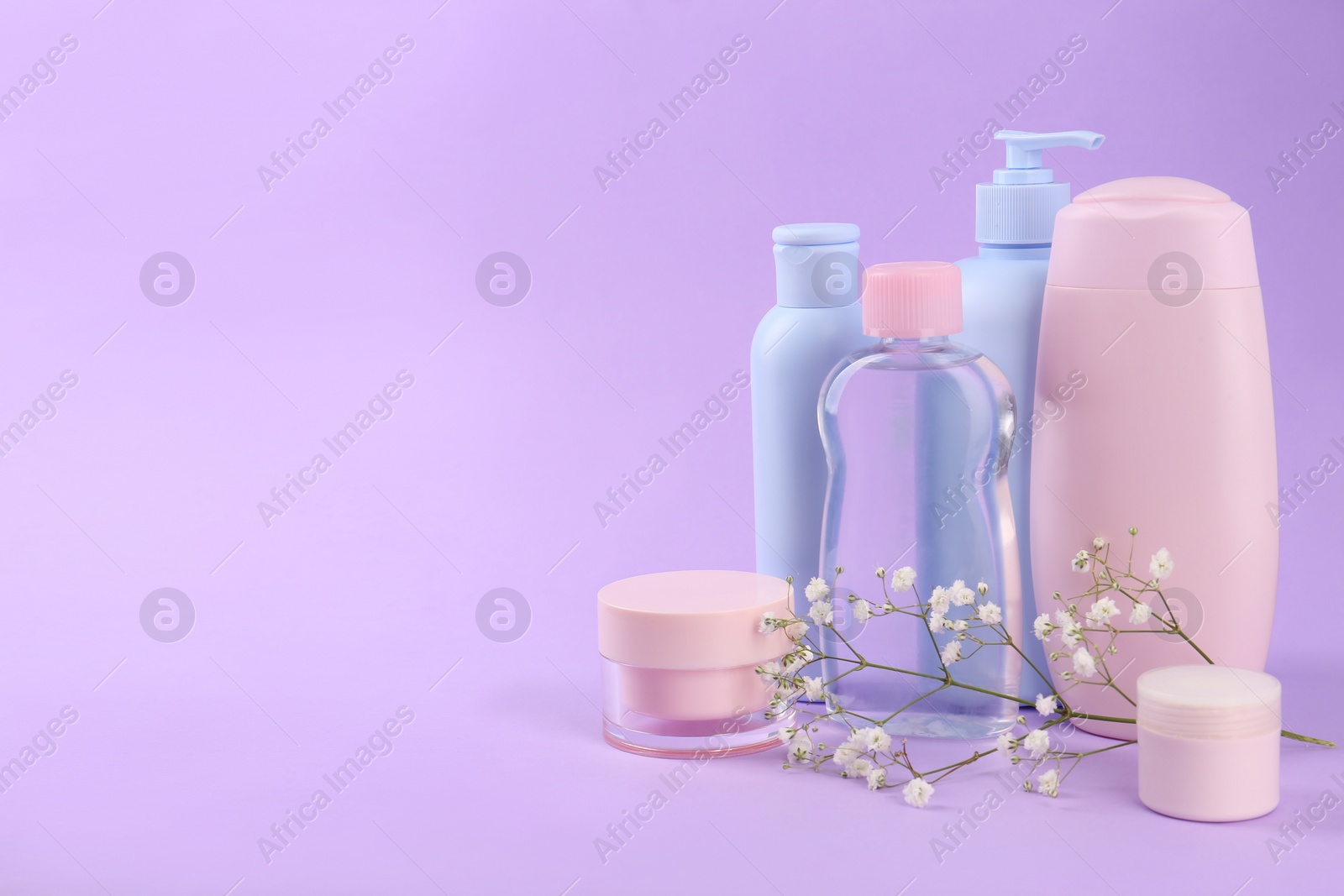 Photo of Different skin care products for baby and gypsophila on violet background. Space for text