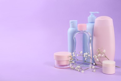 Different skin care products for baby and gypsophila on violet background. Space for text