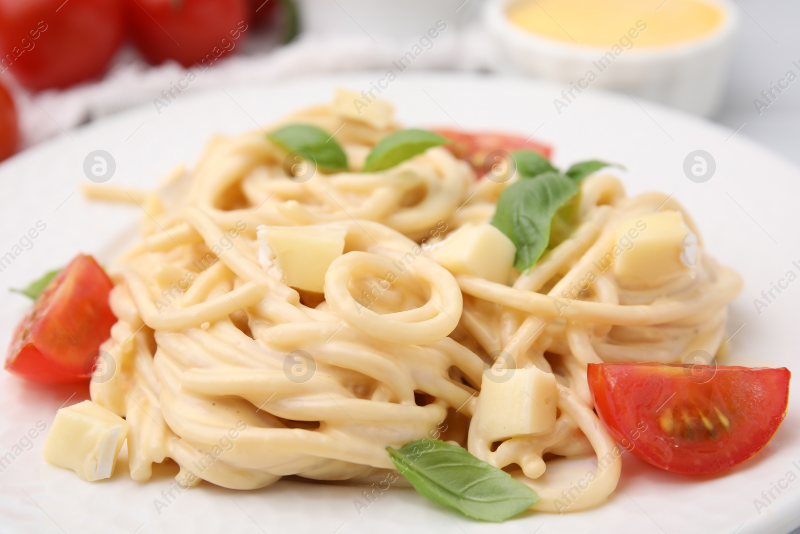 Photo of Delicious pasta with brie cheese, tomatoes and basil leaves on plate, closeup