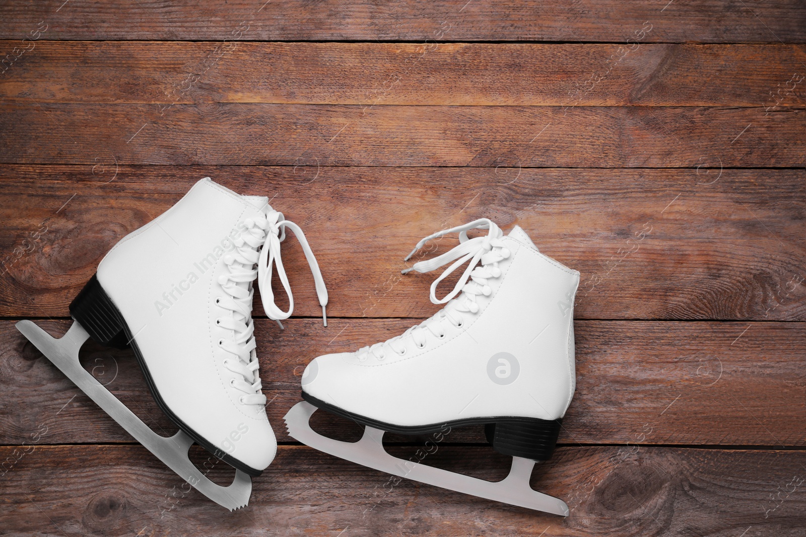 Photo of Pair of white ice skates on wooden background, flat lay