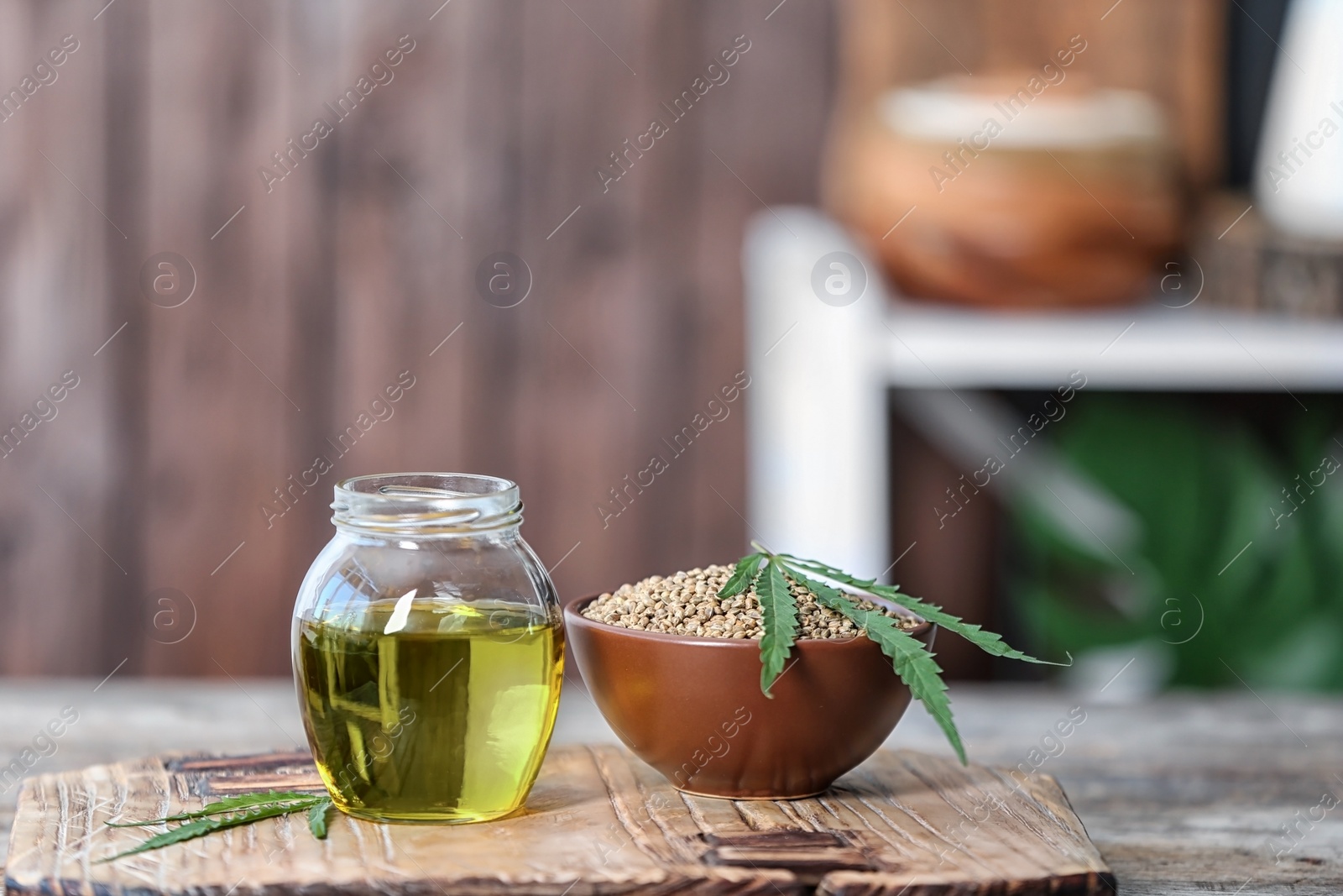 Photo of Jar with hemp oil and bowl of seeds on wooden table