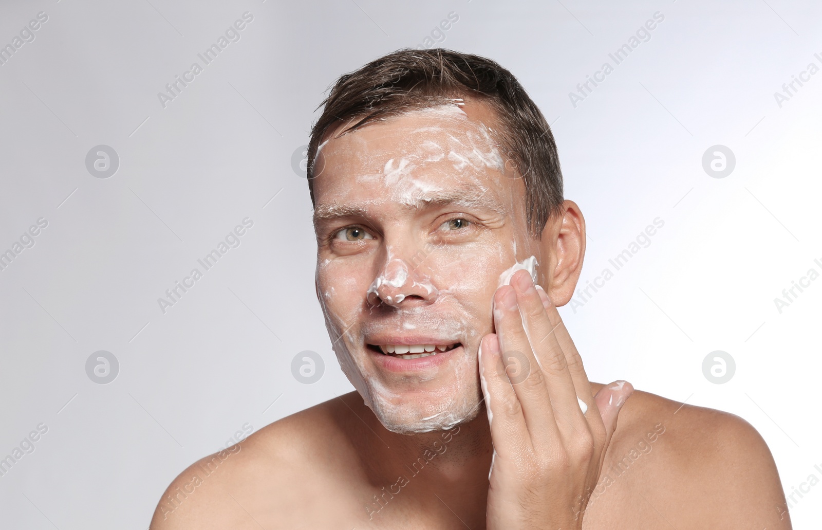 Photo of Man washing face with soap on white background