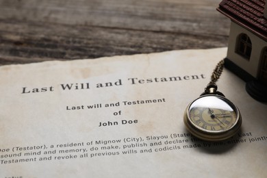 Photo of Last Will and Testament with pocket watch and house model on wooden table, closeup