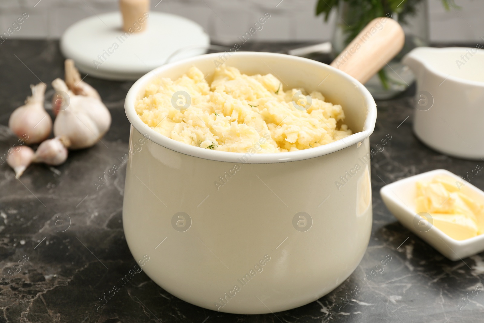 Photo of Saucepan with tasty mashed potato on dark table