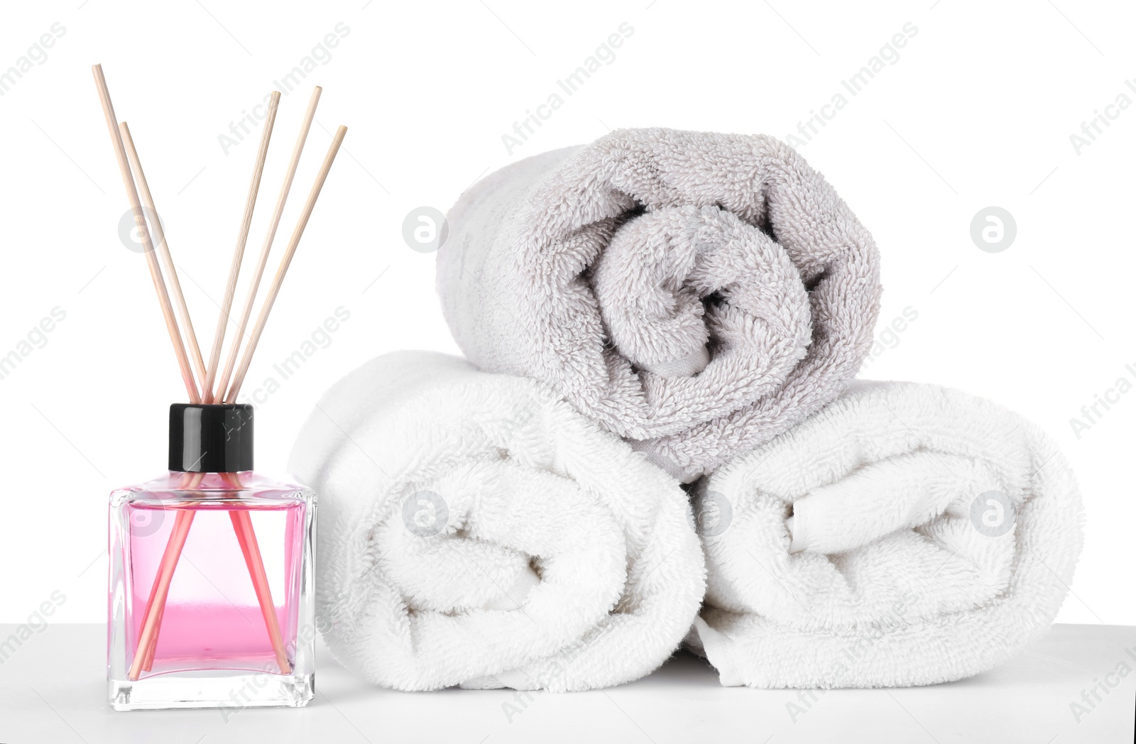 Photo of Fresh towels and reed air freshener isolated on white