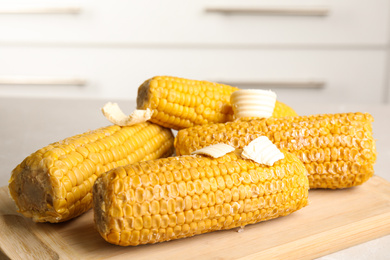 Delicious boiled corn with butter on wooden board