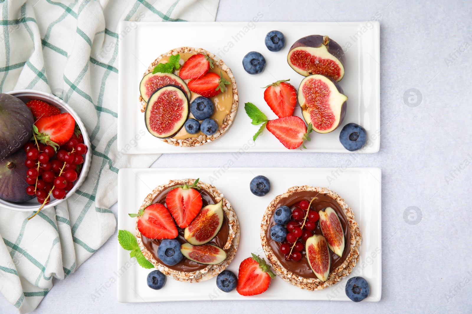 Photo of Tasty crispbreads with different toppings served on light table, flat lay