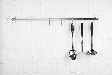 Photo of Rack with clean kitchen utensils on white white wall. Space for text