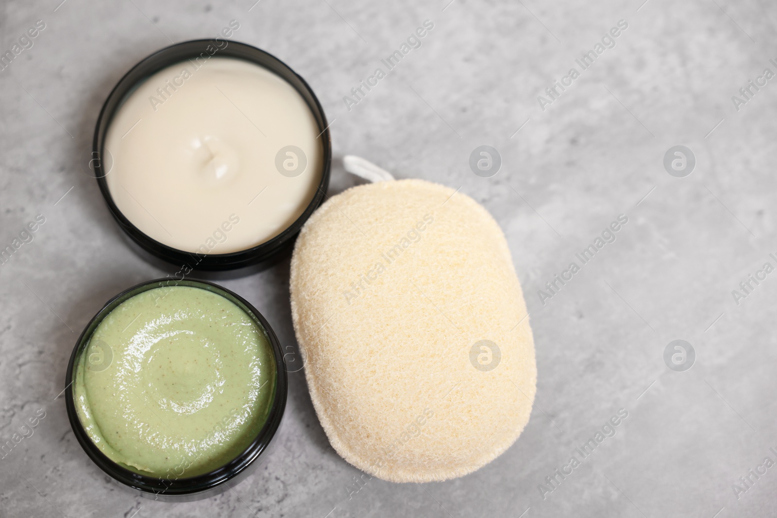 Photo of Natural body scrub, cream and sponge on grey table, above view. Space for text