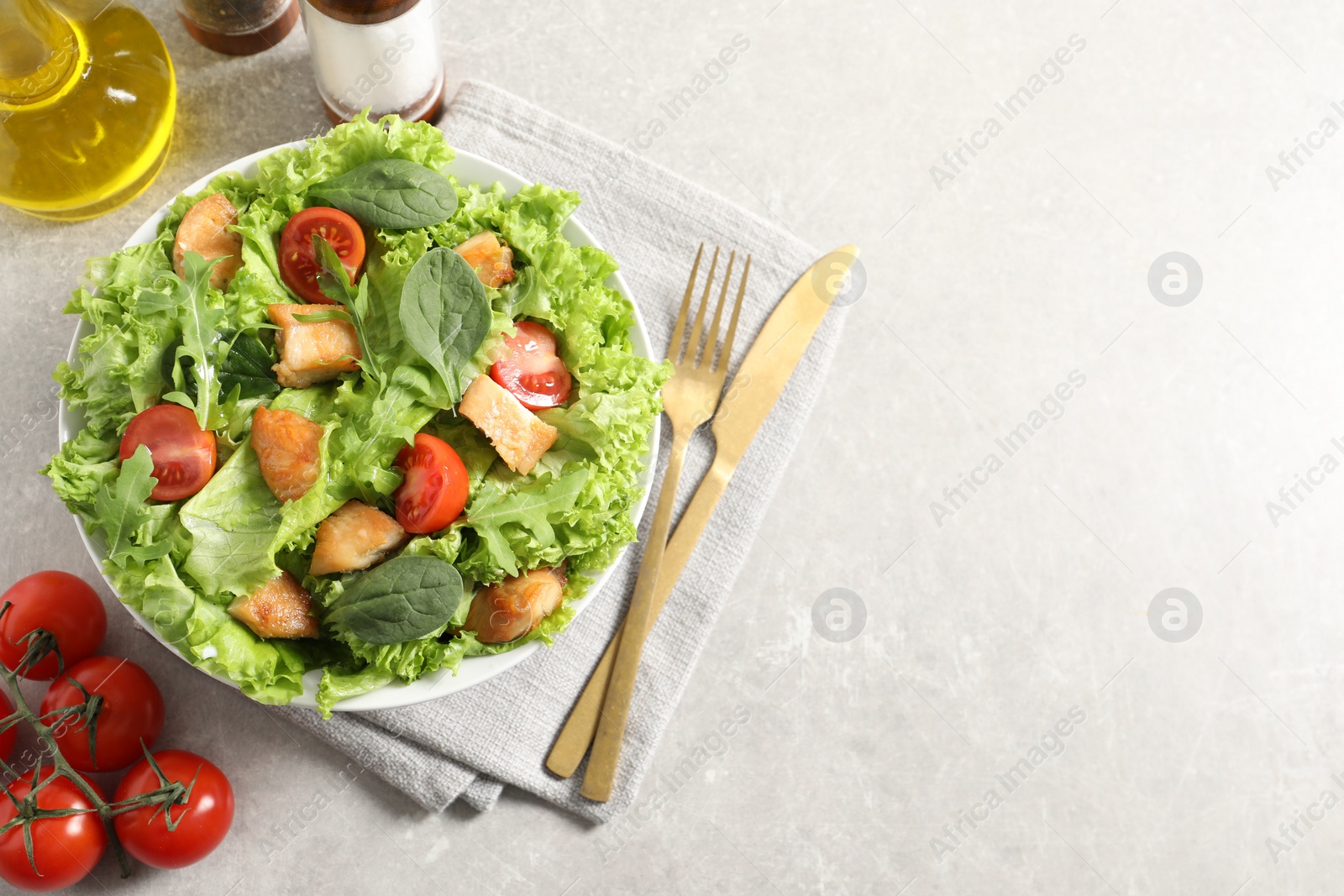 Photo of Delicious salad with chicken, cherry tomato and spinach served on light grey table, top view. Space for text