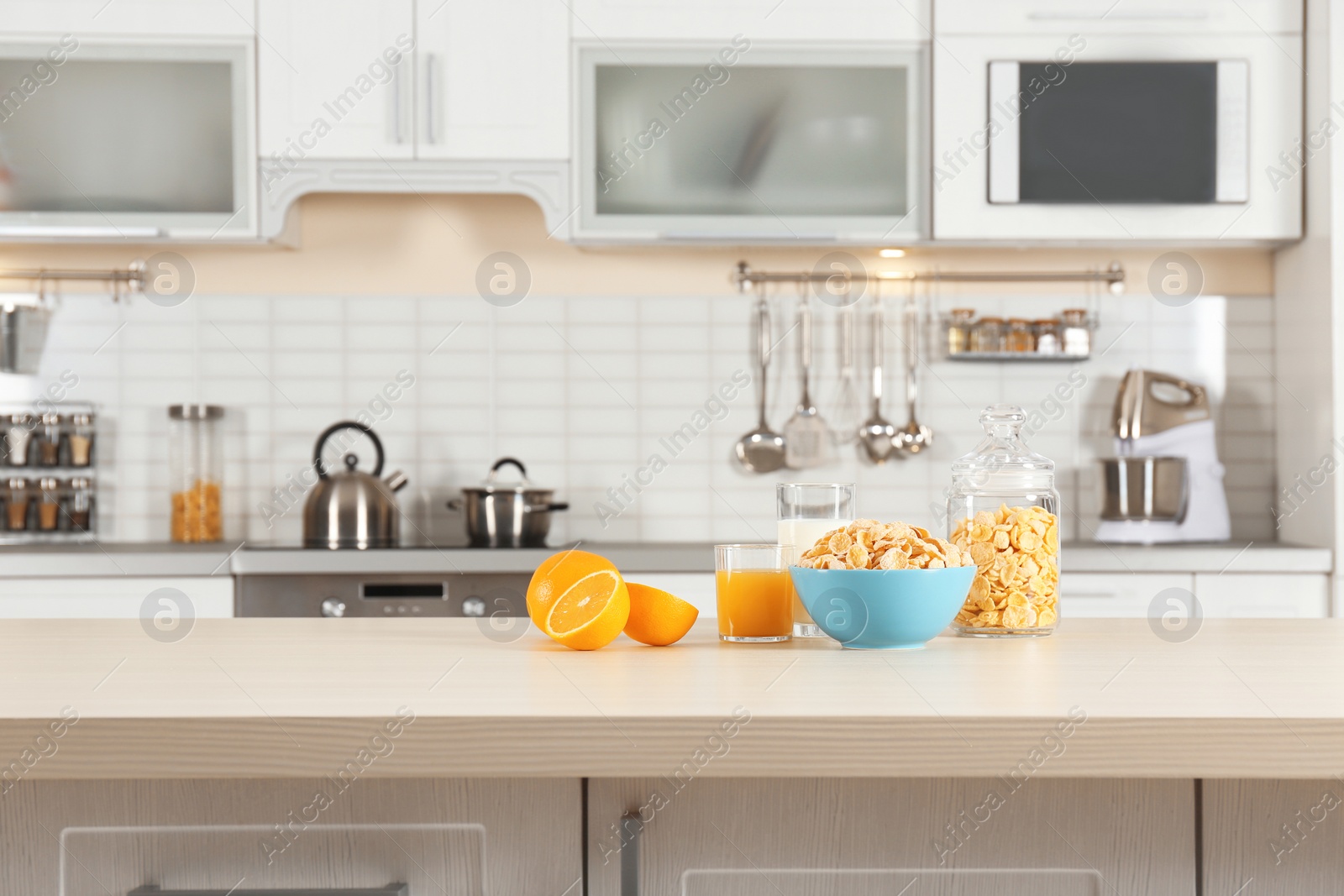 Photo of Cornflakes with glasses of juice and milk on kitchen table