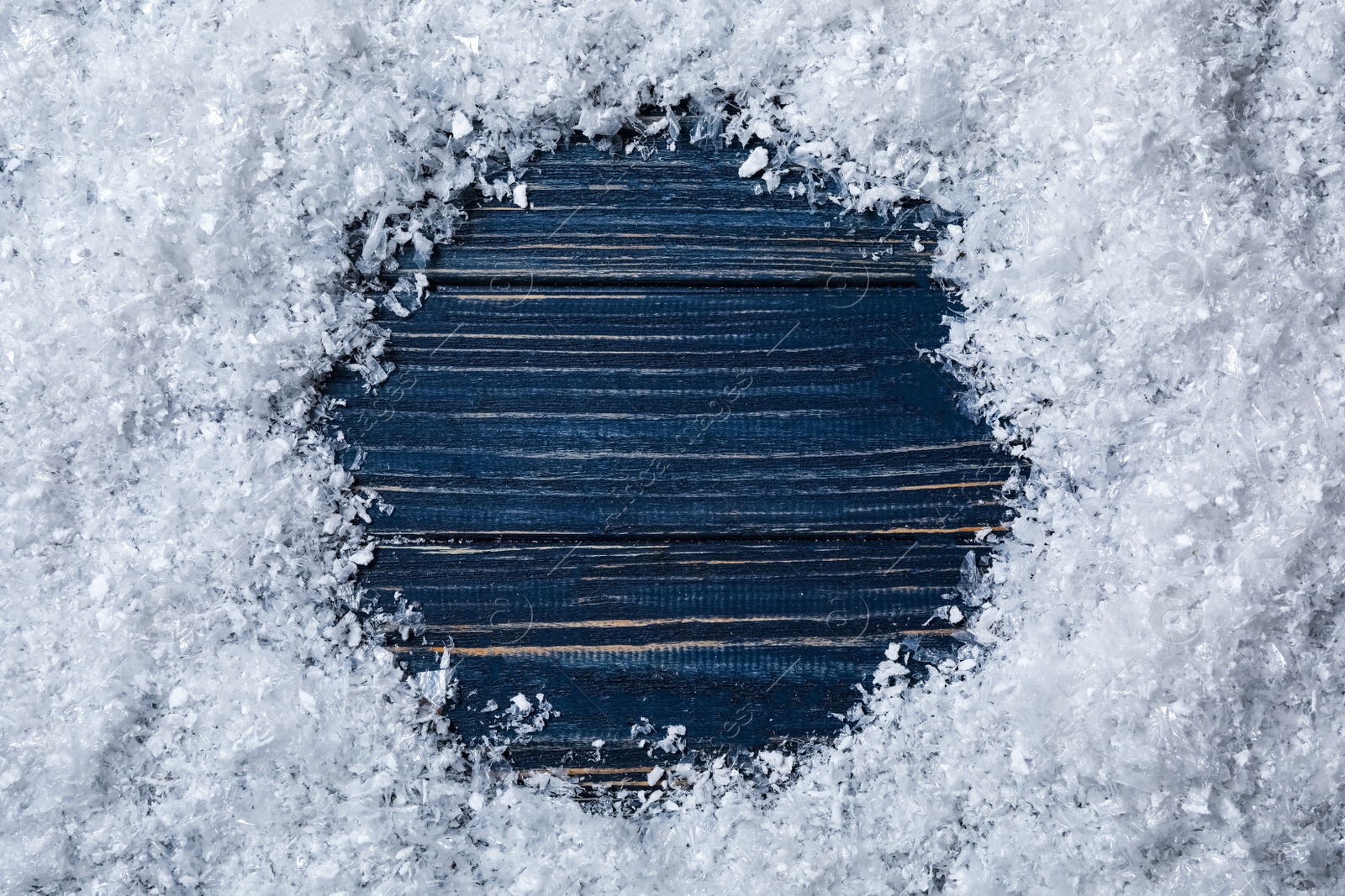 Photo of Frame made of snow on blue wooden background, top view with space for text. Christmas time