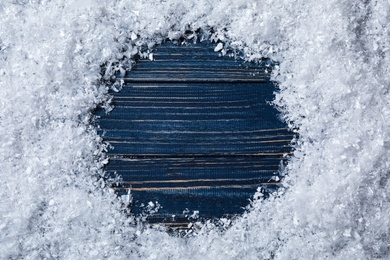 Frame made of snow on blue wooden background, top view with space for text. Christmas time