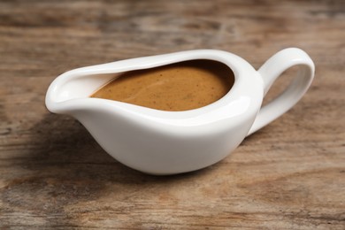 Photo of Delicious turkey gravy in sauce boat on wooden table