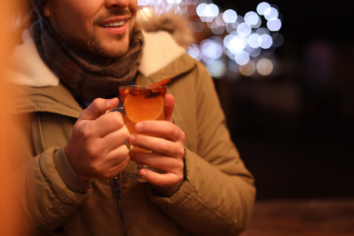Photo of Man with tasty mulled wine at winter fair, closeup