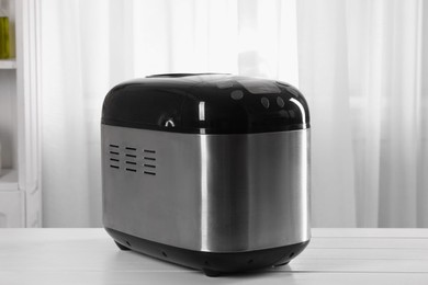 Modern breadmaker on white wooden table indoors