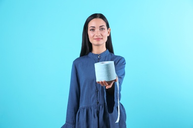 Photo of Beautiful woman holding toilet paper roll on color background