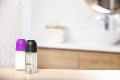 Photo of Roll-on deodorants on wooden table in bathroom, space for text