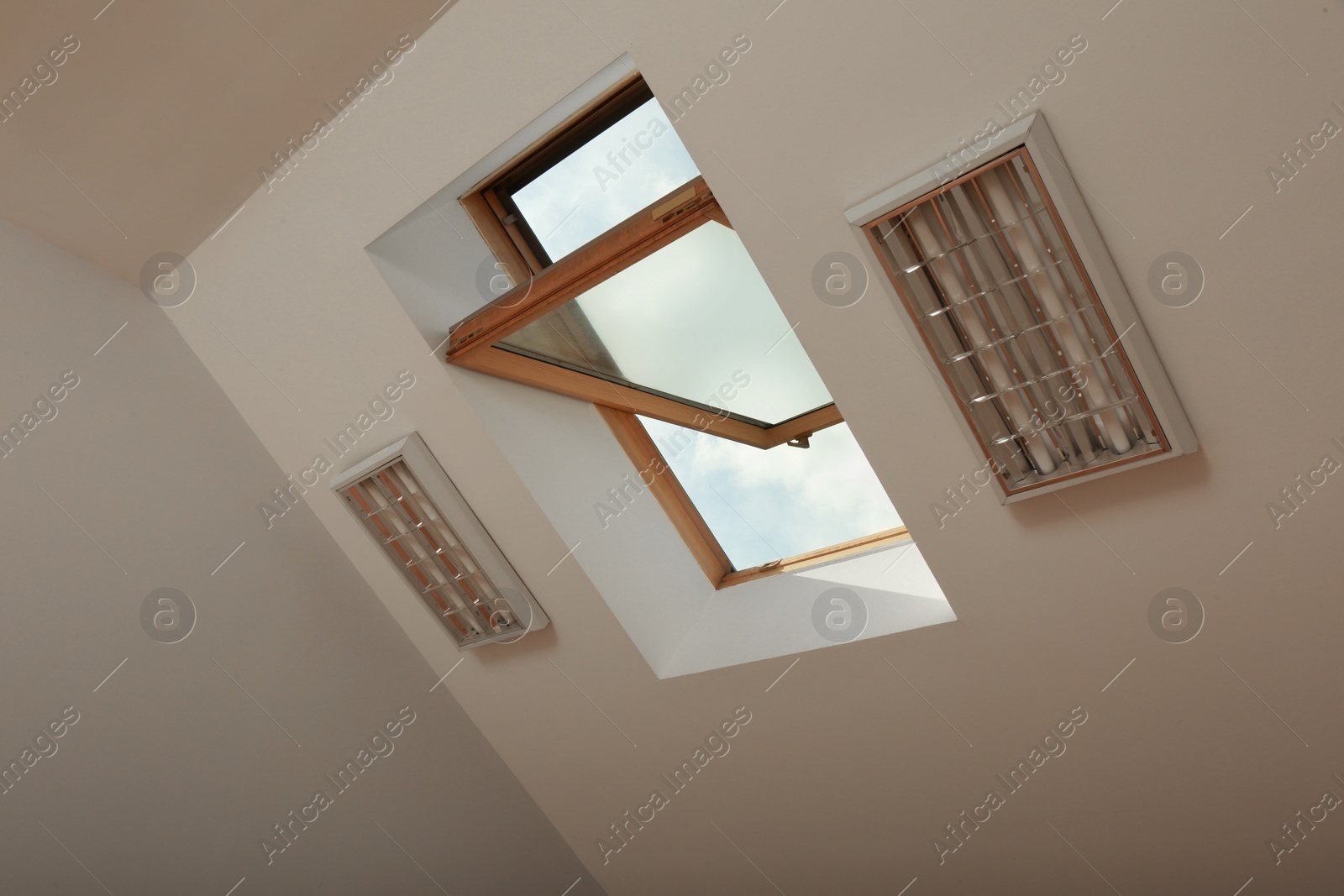 Photo of Open skylight roof window on slanted ceiling in attic room, low angle view