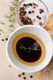 Photo of Bowl of organic balsamic vinegar with oil, spices and bread slices on beige table, flat lay